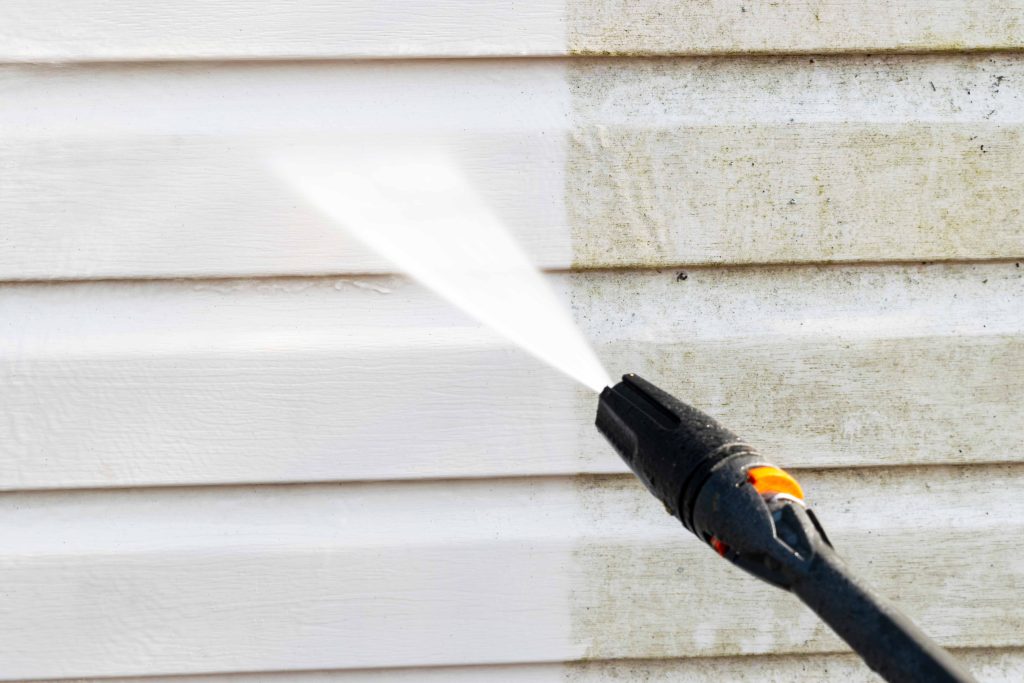 Expert high-pressure nozzle treatment on home siding in South Florida, revealing a cleaner and rejuvenated exterior