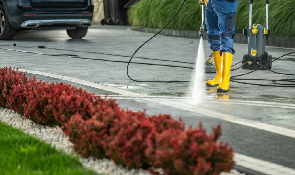 Worker Power Washing Residential Driveway